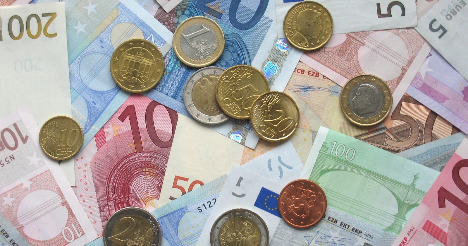Monety i banknoty euro rozłożone na stole.